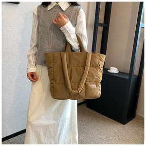 Macro detail of khaki quilted puffer tote bag with glossy nylon finish and fashion label