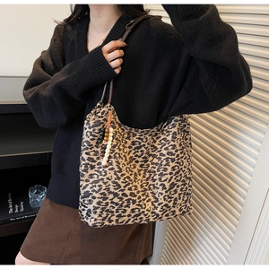 Detail of leopard print tote bag with wooden bead tassel charm and leather handles