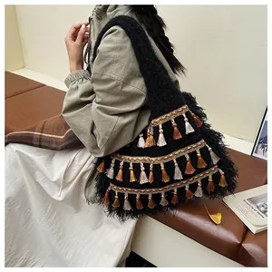 Detail of knit tote bag with bohemian tassels and embroidery on model in home setting