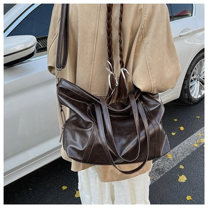 Sac fourre-tout en cuir vintage marron foncé avec bandoulière, porté par un mannequin en ville