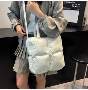 Detail of white quilted puffer bag featuring a soft padded handle and crossbody strap