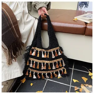 Detail of a black knit tote bag with bohemian colorful tassels in an autumn scene