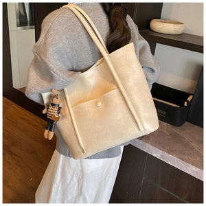 Detail of cream tote bag featuring a magnetic pocket and a cute rabbit doll charm