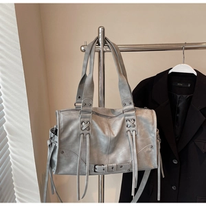 Detail of vintage grey leather pillow bag featuring long tassels and retro silver hardware
