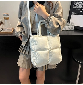 Close-up of white quilted puffer tote bag with fluffy texture and thin shoulder strap