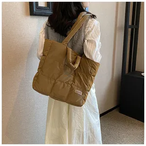 Detailed view of brown quilted tote bag with square pattern and adjustable shoulder strap