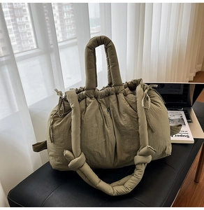 Detail view of olive green quilted puffer tote bag on a bench in a modern room