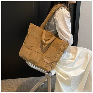 Macro view of brown quilted tote bag with soft padded puffer texture and fashion label