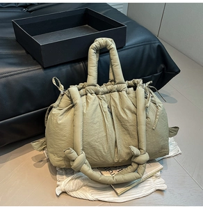 Detail of olive green quilted puffer bucket bag featuring drawstring closure and knotted strap