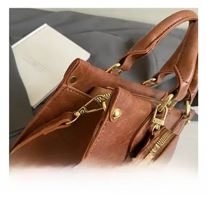 Close-up of golden metal hooks and handle detail on brown vintage leather crossbody bag