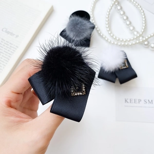 Détail d'une pince à cheveux en fourrure de vison avec nœud noir et boucle en perle