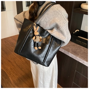 Detail view of large black retro tote bag with wrinkled texture and cute bunny pendant