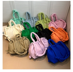 Detailed pile of colorful quilted puffer bucket bags showing soft texture and drawstring