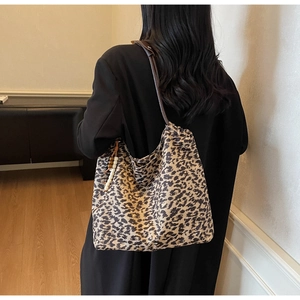 Detail of leopard print tote bag with wooden bead charm on a shoulder strap