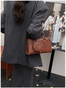 Street style shot of a vintage brown leather tote bag with a matching coin purse charm