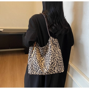 Close-up of leopard print tote bag with brown leather straps and wooden bead pendant