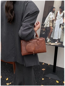 Detailed view of brown PU leather square bag with pleated texture and mini round charm
