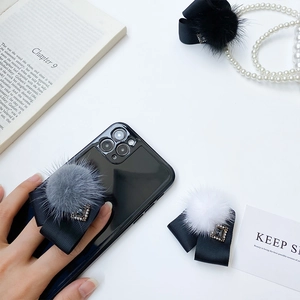 Support de téléphone avec nœud en fourrure de vison et strass sur fond blanc