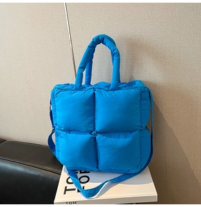 Close-up of vibrant blue quilted puffer tote bag with adjustable shoulder strap and handles