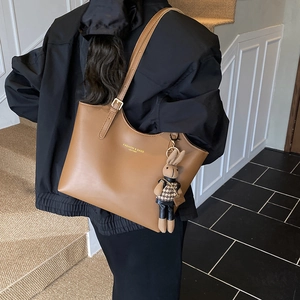 Brown leather tote bag with rabbit charm and gold lettering shown on shoulder
