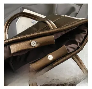 Detailed view of the magnetic snap closure and metallic quilted fabric on the tote bag