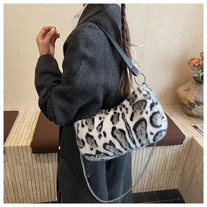 Détail du sac léopard en peluche avec chaîne argentée porté sur un blazer gris