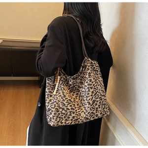 Detail of leopard print tote bag with brown shoulder strap and beaded tassel charm