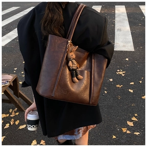 Close-up of deep brown leather tote bag with a cute rabbit charm and golden hardware