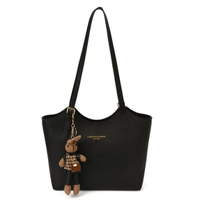 Minimalist black leather tote bag with gold lettering and cute bunny charm on white background