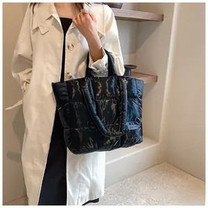 Close-up of black quilted puffer tote bag with glossy finish and fashion logo detail
