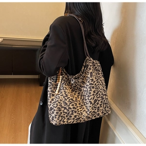 Detail of leopard print tote bag with beaded tassel and leather strap on model