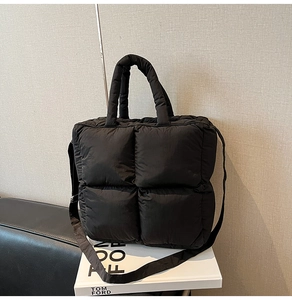 Detail of black quilted puffer bag with large square stitching and padded handle