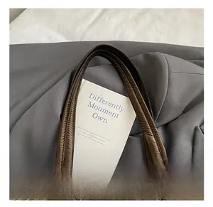 Close-up of padded top handle on quilted metallic bronze tote bag with detailed stitching