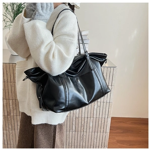 Detail of a minimalist black PU leather tote bag with metallic buckle and soft texture