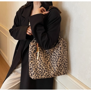 Detail of leopard print tote bag with decorative beaded tassel and brown strap