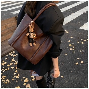 Close-up of a large brown vintage leather tote bag with a cute rabbit doll charm