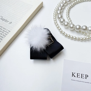 Détail d'un nœud en ruban noir avec pompon en fourrure blanche et perle dorée élégante