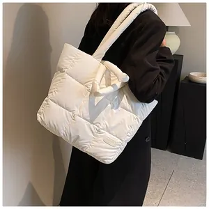 Detail of white quilted puffer tote bag with fashion patch and padded handles