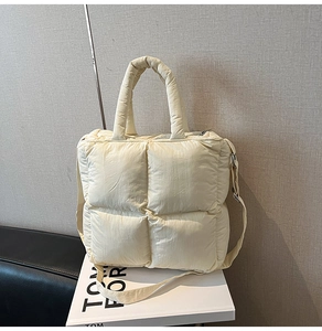Detailed view of beige quilted puffer tote bag with thick padded handles and nylon texture