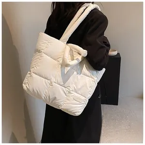Detail of white quilted tote bag featuring a stitched 'FASHION' label and puffer texture