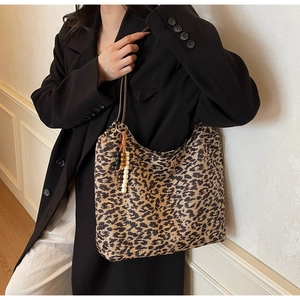 Detail of large leopard print tote bag with a decorative wooden bead charm