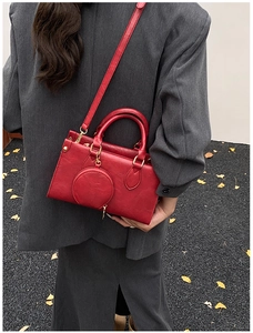 Macro detail of red textured leather handbag with a small round pouch and gold hardware