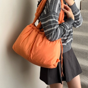 Quilted orange puffer tote bag with knotted strap detail for casual everyday style