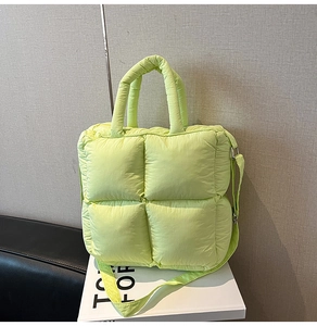 Detail of lime green quilted puffy tote bag with top handle and adjustable strap