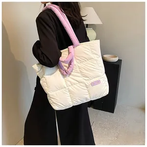Quilted puffer tote bag in cream with purple handles worn by model in a modern home