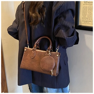 Detail view of retro brown textured leather crossbody bag with a round charm purse