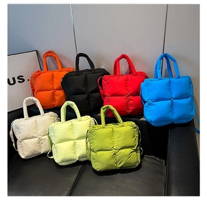 Collection of colorful quilted puffer tote bags with cross-body straps on a sofa