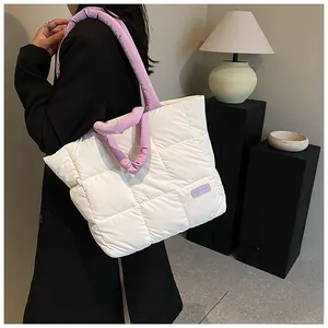 Close-up of quilted tote bag featuring white padded fabric and purple handles with fashion patch
