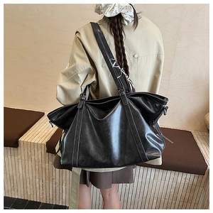Detailed view of black oil wax leather tote bag with subtle side zipper and strap accents