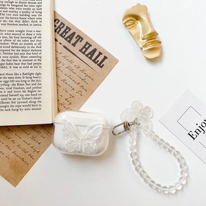 Detailed view of clear AirPods Pro case with white butterfly embroidery and pearl strap